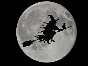 čarodějnice s kočkou letí na koštěti okolo Měsíce
